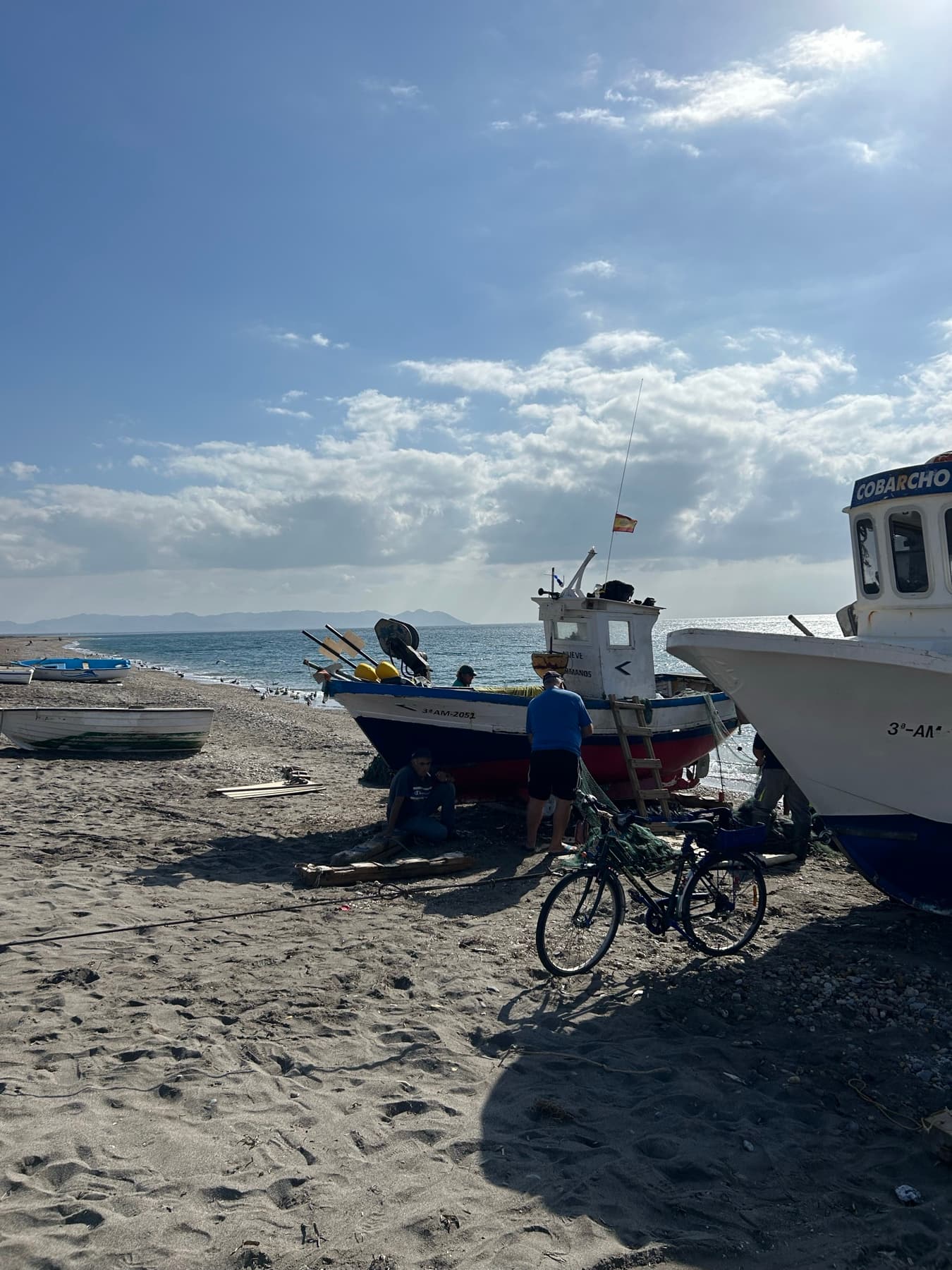 Bicicleta en la playa junto a barcos de pesca