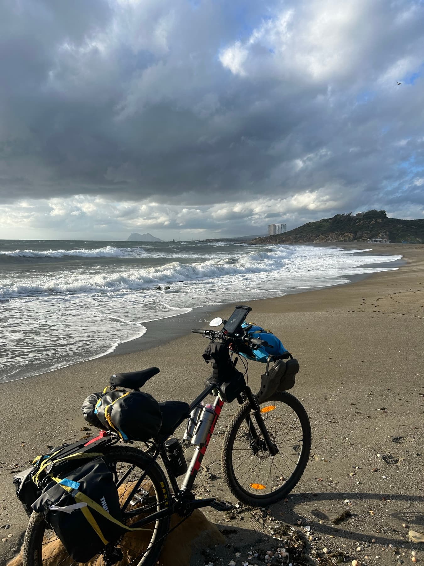 Bicicleta cargada ante una playa con cielo de tormenta