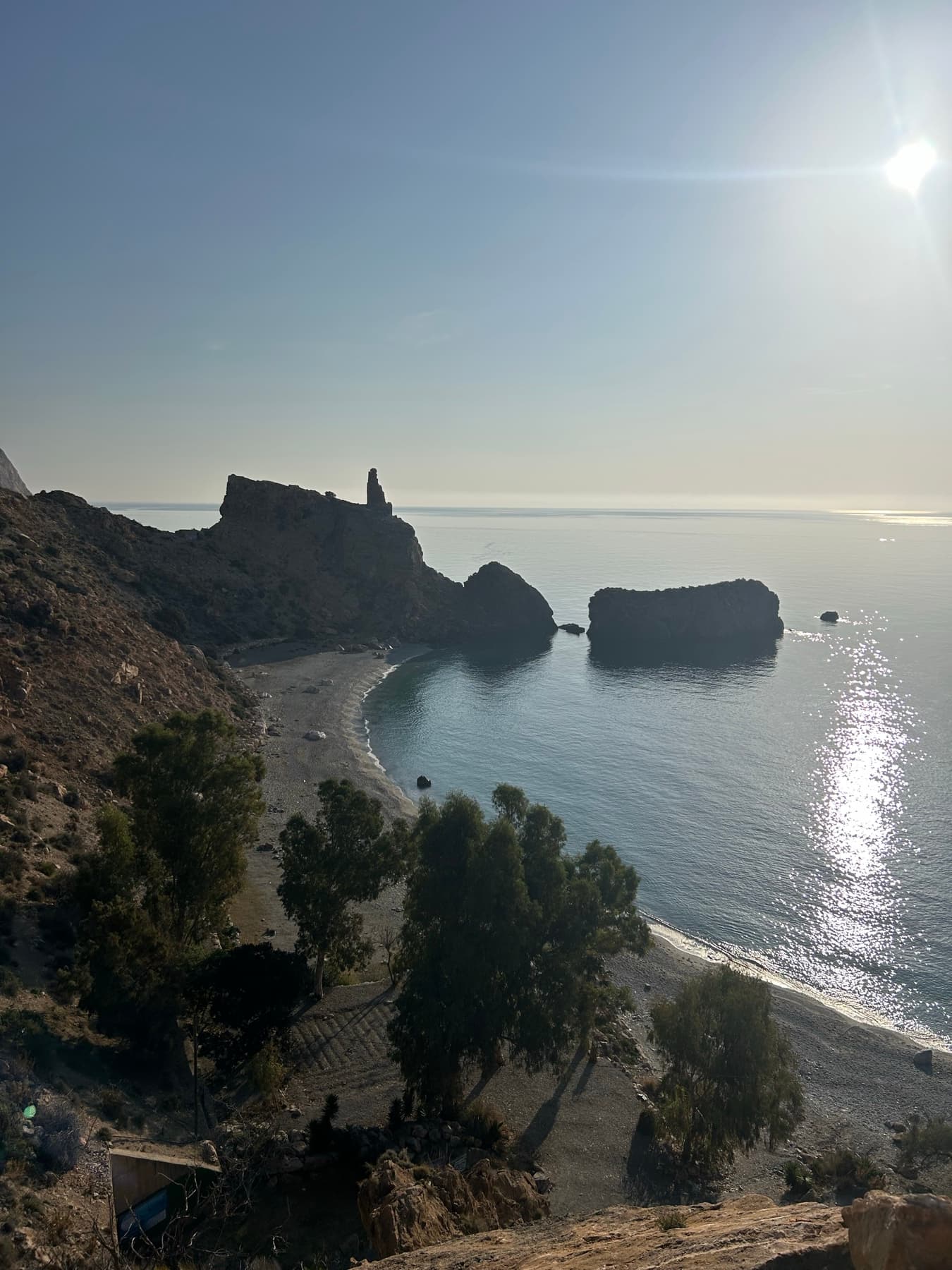 Cala entre rocas con el sol reflejado en el agua