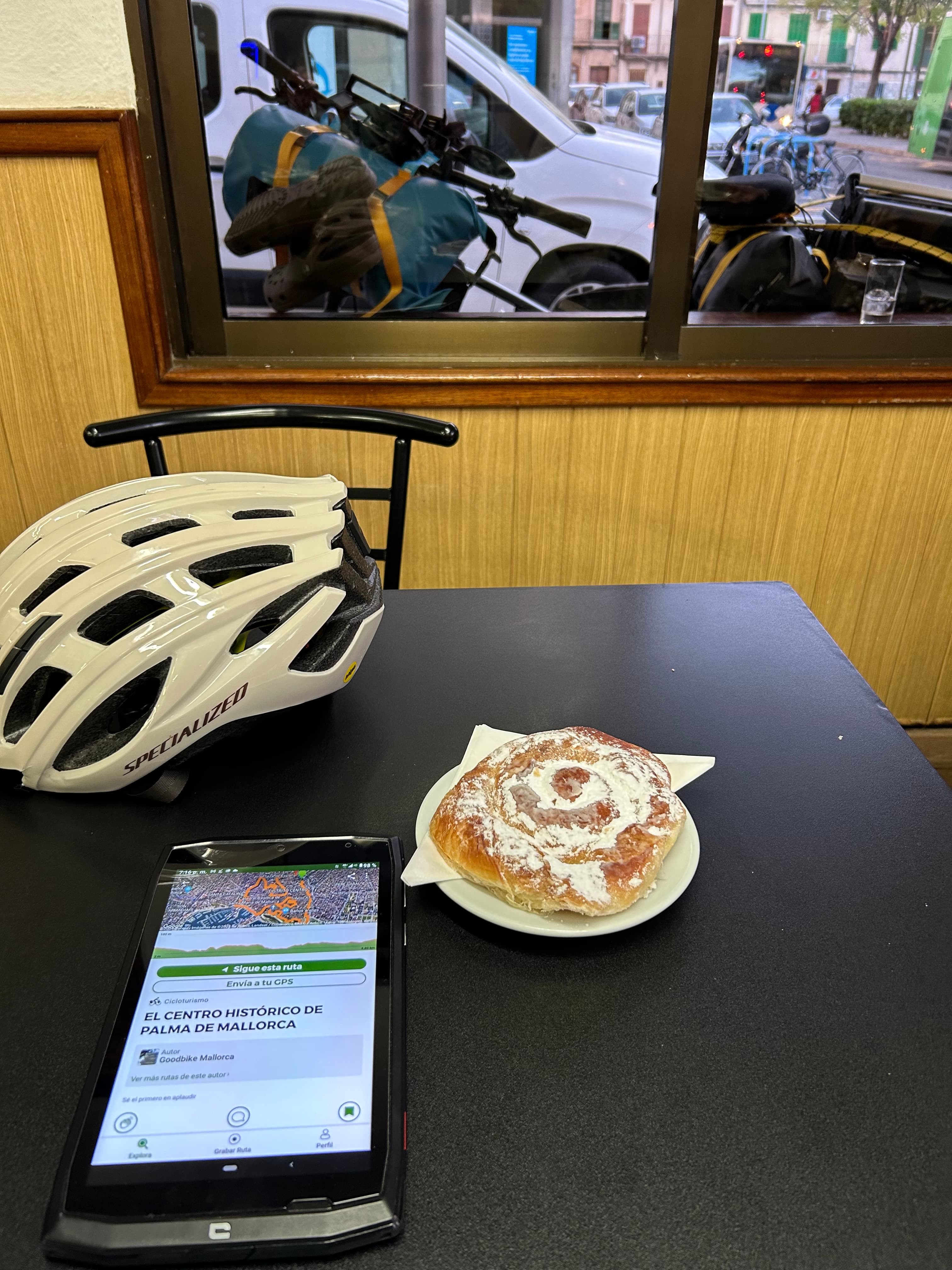 Ensaimada, casco y pantalla de ruta sobre una mesa