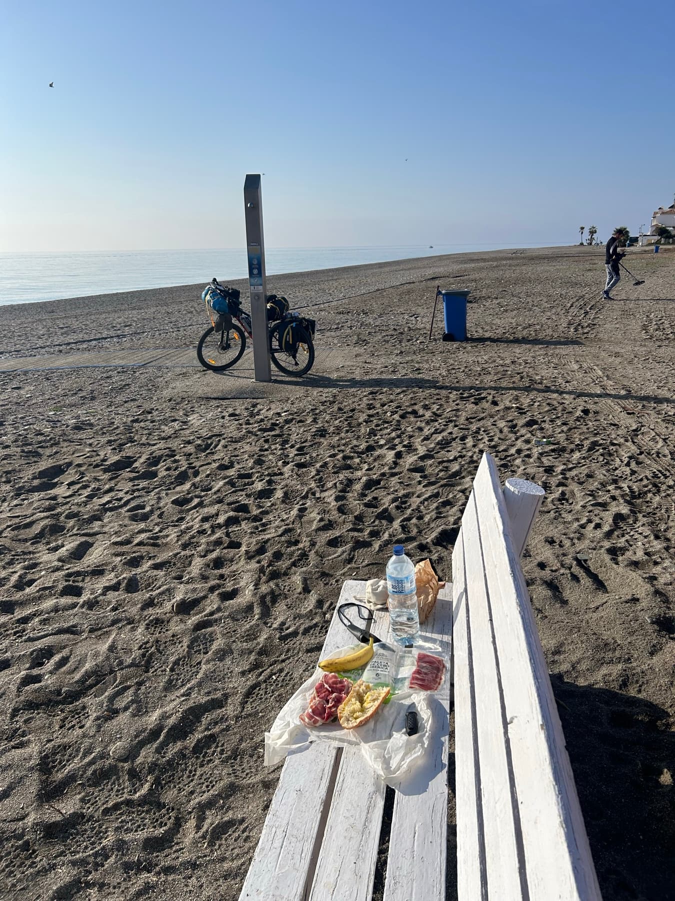 Comida en un banco de playa con la bicicleta al fondo