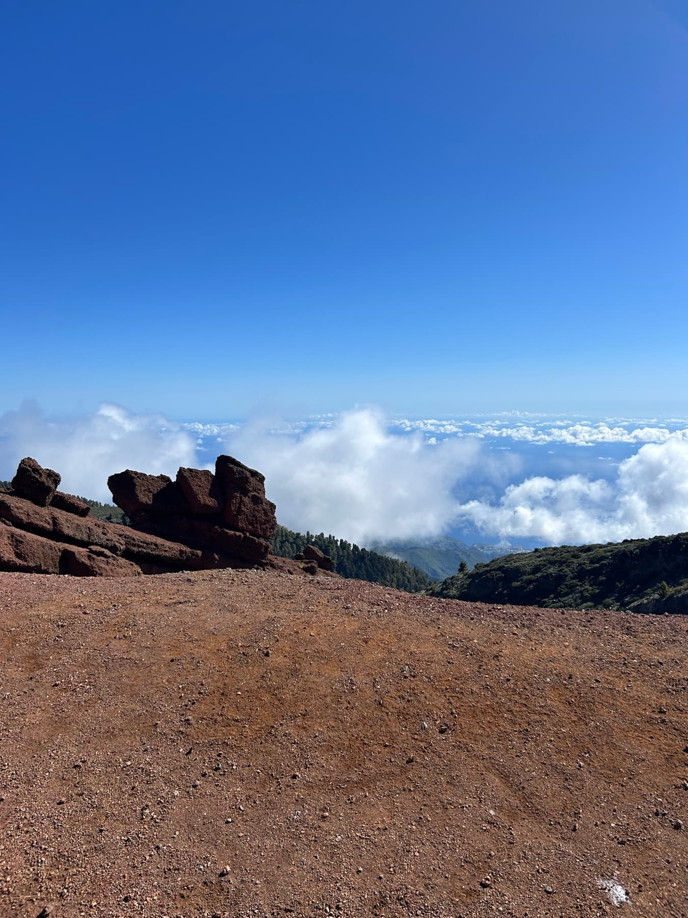 Roca volcánica roja sobre un mar de nubes