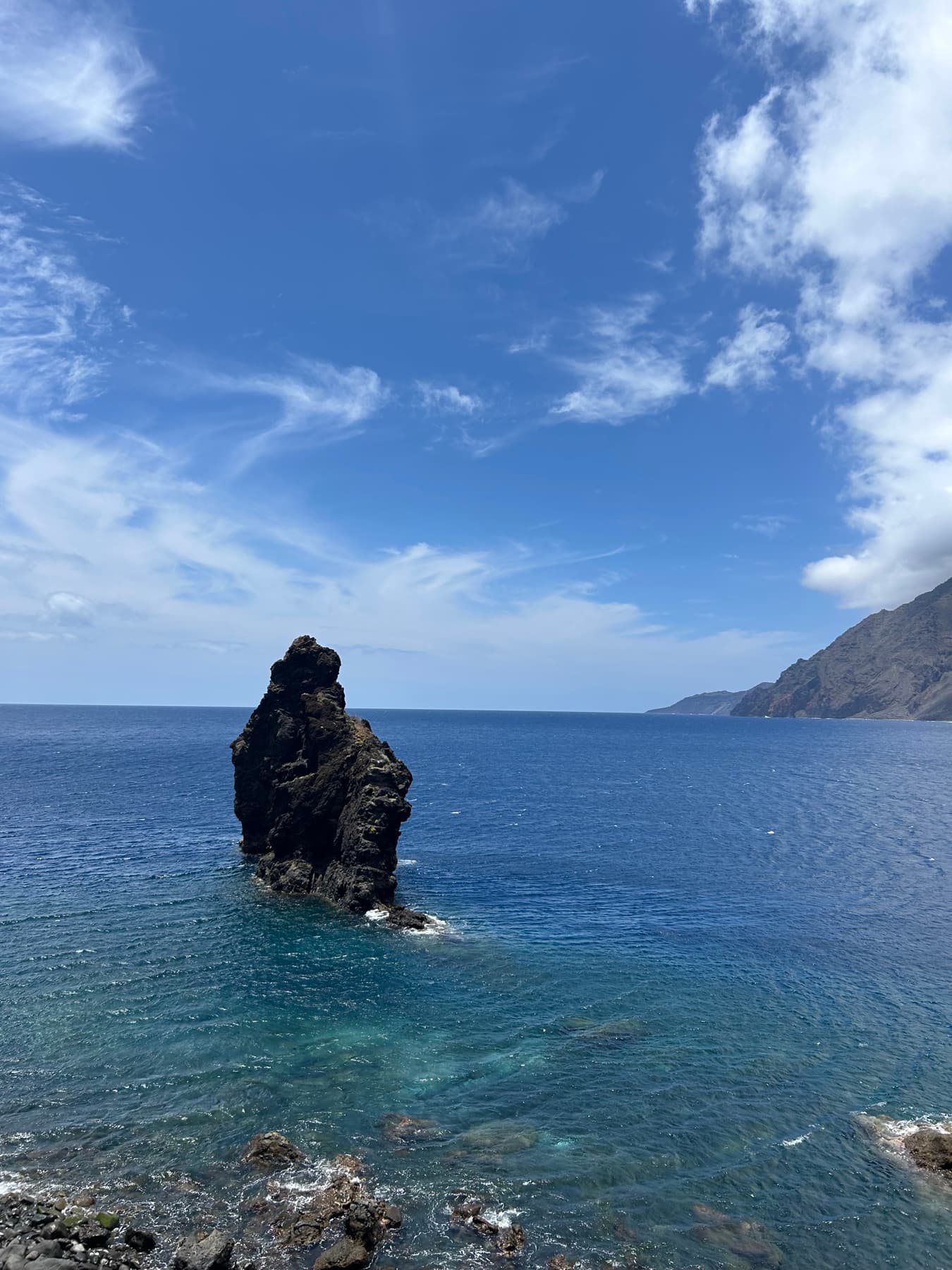 Roque en el mar bajo cielo azul